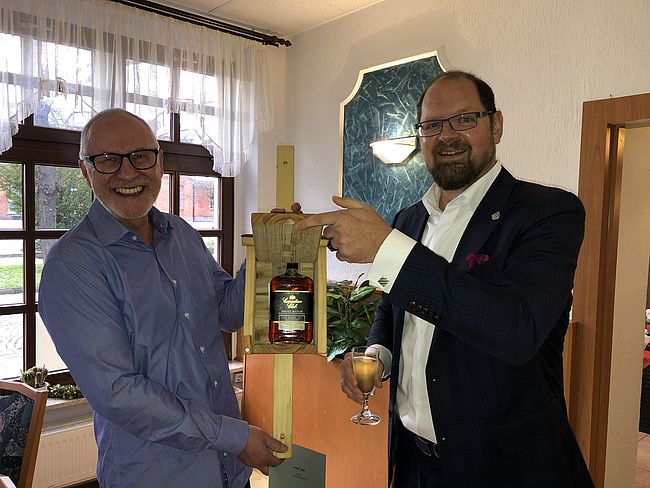 Das Foto zeigt Landrat Martin Stichnoth und Frank Schulze. Stichnoth überreicht sein Abschiedsgeschenk, ein Vogelhaus, darin eine Flasche Whisky. 