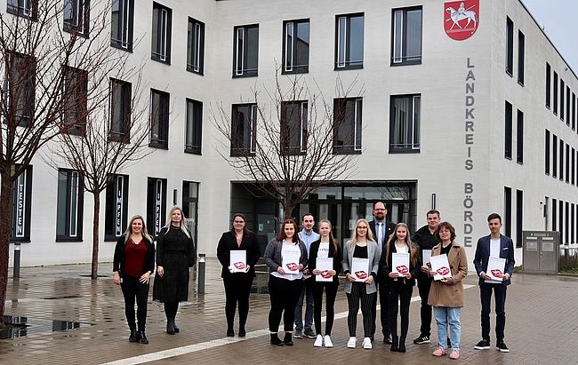 Aufstellung zum Erinnerungsfoto vor dem Haupteingang der Kreisverwaltung in Haldensleben / die angehenden Auszubildenden haben ihre Verträge in den Händen /  v. l. n. r. Ausbildungsleiterin Manuela Brasch, Julia Herzberg-Ebeling (Leiterin Personalamt), Charlotte Borchert, Lena Markworth, Andi Zefi, Sophie Schönduwe, Nora Mühlmann, Landrat Martin Stichnoth, Emma Müller, Julian Dehne, Hannah Rasche und Florian Ebeling  
