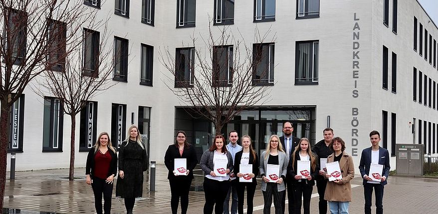 Aufstellung zum Erinnerungsfoto vor dem Haupteingang der Kreisverwaltung in Haldensleben / die angehenden Auszubildenden haben ihre Verträge in den Händen /  v. l. n. r. Ausbildungsleiterin Manuela Brasch, Julia Herzberg-Ebeling (Leiterin Personalamt), Charlotte Borchert, Lena Markworth, Andi Zefi, Sophie Schönduwe, Nora Mühlmann, Landrat Martin Stichnoth, Emma Müller, Julian Dehne, Hannah Rasche und Florian Ebeling  