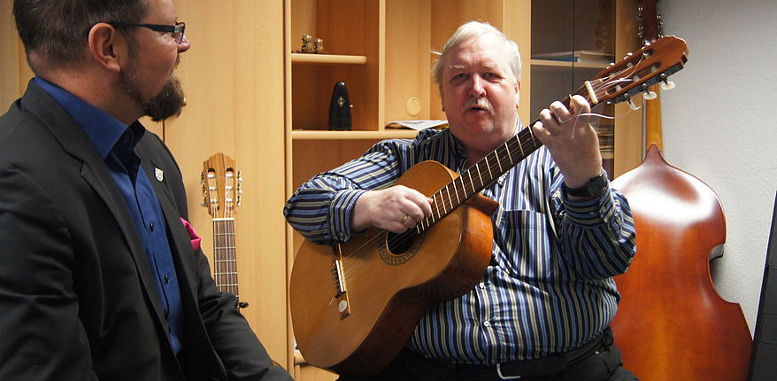 Das Foto zeift Musikschulleiter Armin Hartwig mit der Gitarre in den Händen. Daneben Landrat Martin Stichnoth. 