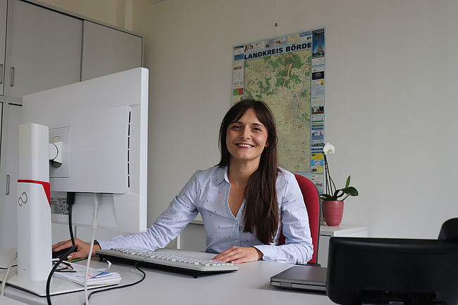 Gleichstellungsbeauftragte Katja Klommhaus sitzt in ihrem Büro am Schreibtsich. Sie sagt im Kontext zum Internationalen Frauentag 2022 "Weil wir es uns wert sind!"