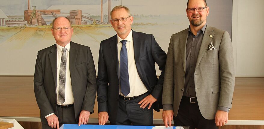 Foto Thorsten Kowalowka (Kaliwerk Zielitz) Landrat Martin Stichnoth und Thomas Webel verabschieden Dr. Holger Hoppe nach Kassel. Die drei stehen mit einem Bild von der Kalihalde als Abschiedsgeschenk nebeneineander.
