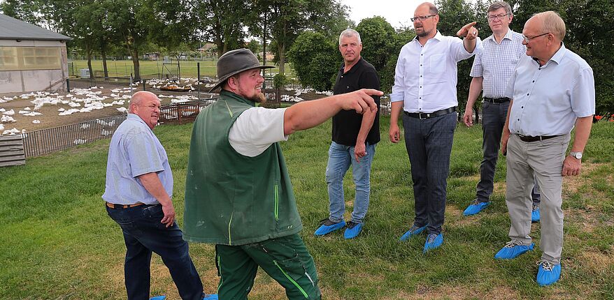 Foto Ottfried Junge / Stippvisite in Wulferstedt, von rechts: Hans Walker, Dr. Wolfgang Nehring, Landrat Martin Stichnoth, Guido Heuer-MdL, Hagen Müller sowie Rüdiger Breier. Die Herren stehen auf einer Wiese am Hang, im Hintergrund ist Geflügel in Freilandhaltung zu sehen.