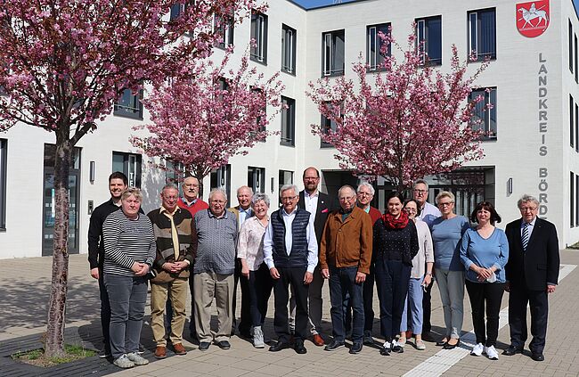Foto Uwe Baumgart / Aufstellung vor dem Verwaltungsgebäude des Landkreises Börde in Haldensleben zum Erinnerungsfoto. In der Mitte, links neben Landrat Martin Stichnoth, steht Ulrich Körber, Vorsitzender des Seniorenrates. Links außen: Dominik Scholz ist in der Verwaltung als Geschäftsstelle für den Kreisseniorenrat verantwortlich  