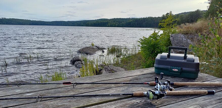 Foto Landkreis Börde / 2 Fischerprüfungen am 4. März 2023 und am 15. April 2023 / Anträge bis 3. Februar 2023 beziehungsweise 17. März 2023 stellen. Im Bild zu sehen, eine Angelkiste auf dem Steg an einem See.