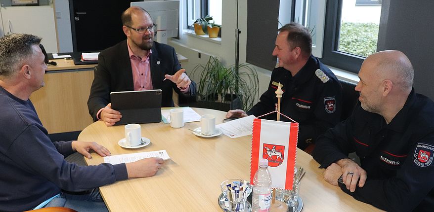 Das Foto zeigt den Beratungstisch des Landrates in Haldensleben. Ralf Lange (links) Dirk Bischoff (rechts) und Kreisbrandmeister Matthias Schumann (neben Bischoff) informieren Landrat Martin Stichnoth über Hilfeleistungen der Feuerwehren infolge des Sturmtiefs "Ylenia".
