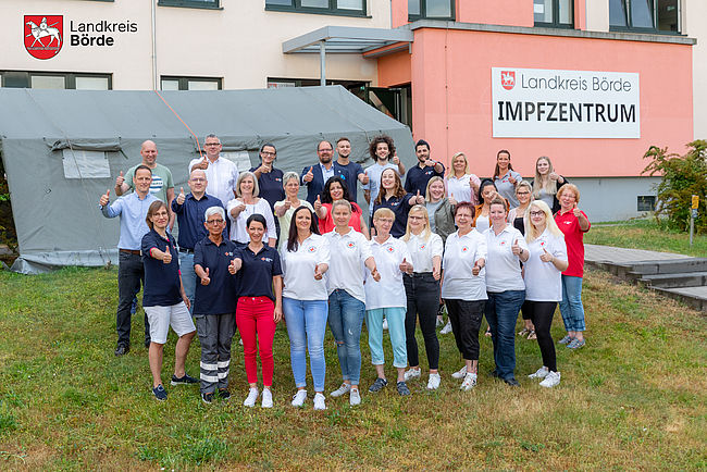 Vor Schließung des Impfzentrums des Landkreises Börde hat das Team in diesen Tagen nochmal Austellung zum Erinnerungsfoto genommen. Das Fotos ist eine Außenaufnahme vor der Fassade des Impfzentrums in Haldensleben auf dem Süplinger Berg. Neben dem Landrat ist das gesamt Team zu sehen. 