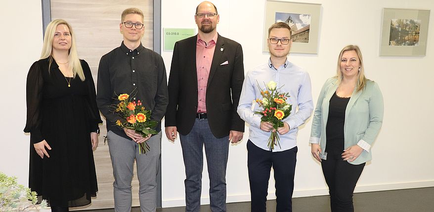 Uwe Baumgart / Landrat Martin Stichnoth, Personalamtsleiterin Julia Herzberg-Ebeling (links) und Ausbildungsleiterin Manuela Brasch (rechts) gratulieren Jannik Gläsmann (links neben dem Landrat) und Tobias Schenke zum Abschuss. Die Absolventen haben Blumensträuße in den Händen. 